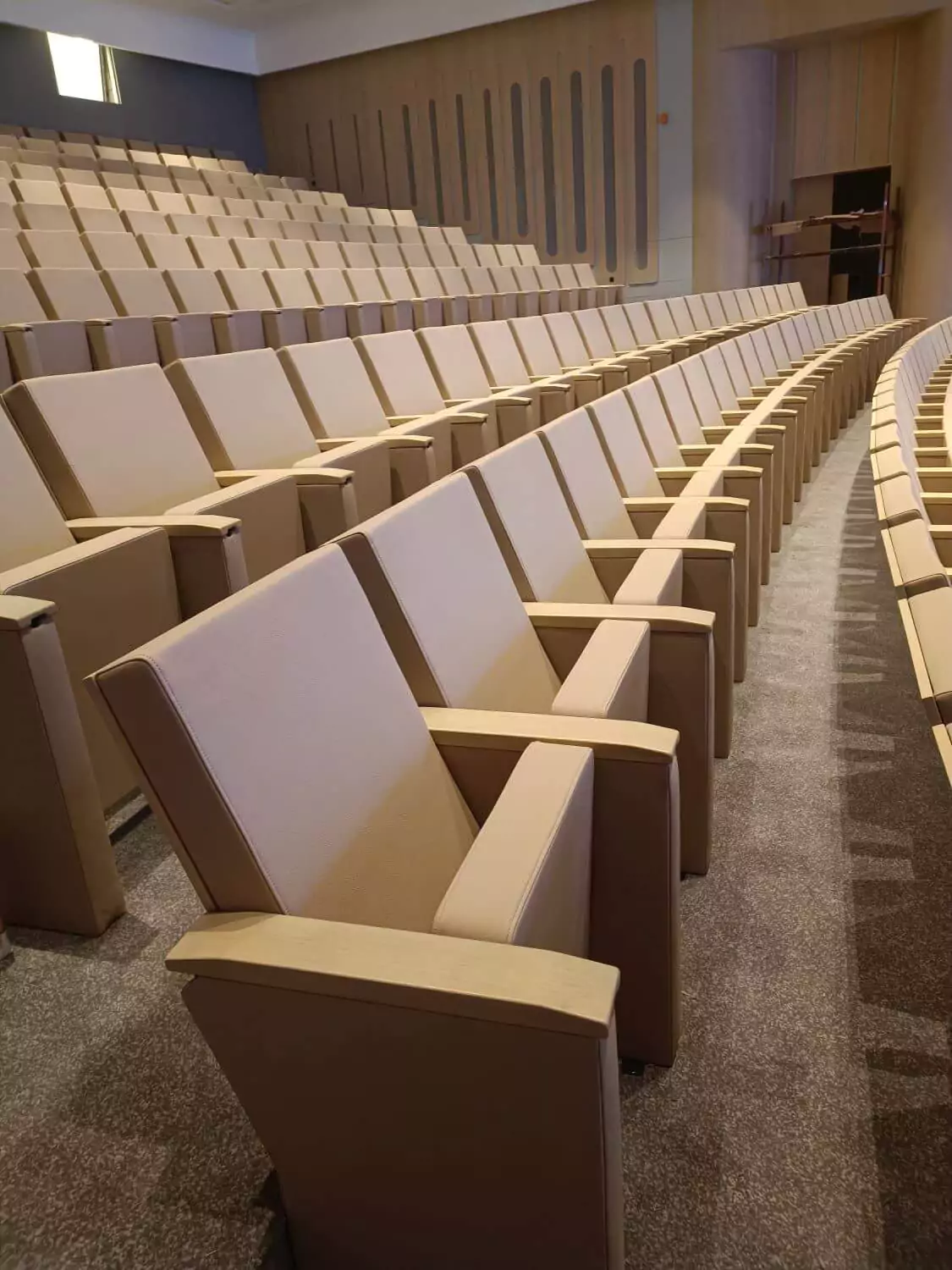 Custom-made conference seats with writing tablets offer practicality and comfort in this large conference room installation. Image